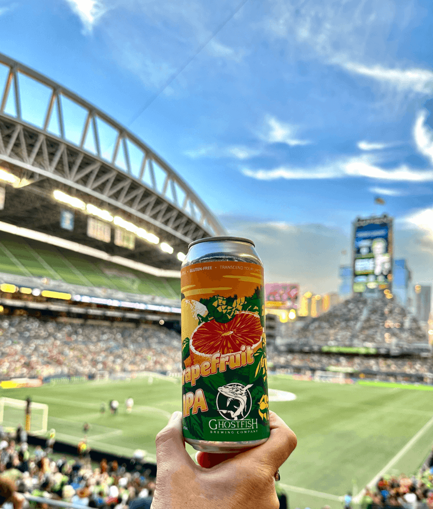 Ghostfish IPA Beer raised in front of Lumen Field